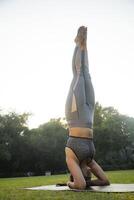 desportivo mulher realizando headstand pose foto