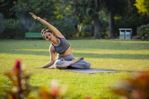 lindo sorrir mulher prática ioga dentro lótus pose alongamento, mãos acima cabeça, inclinado para 1 lado foto
