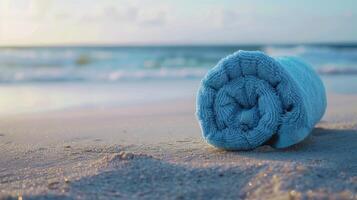 azul toalha enrolado acima em areia perto oceano foto