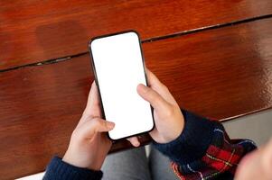 fechar-se tiro do uma mulher usando dela Smartphone às uma mesa, com uma Tela branca Smartphone brincar. foto