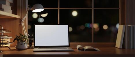 moderno e acolhedor casa escritório área de trabalho às noite com uma Tela branca computador portátil computador em uma madeira mesa. foto