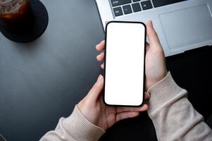 topo Visão imagem do uma mulher segurando uma Smartphone Tela branca brincar sobre a escritório escrivaninha área de trabalho. foto