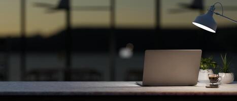 uma moderno, Sombrio escritório área de trabalho às noite características uma computador portátil computador e escuro luz a partir de uma mesa lâmpada. foto