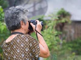 idosos mulher tiroteio foto de digital Câmera às jardim