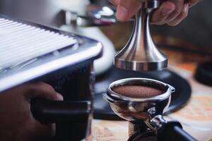 fechar-se do mãos barista prensas terra café usando uma adulterar. a processo do fazer café degrau de degrau foto