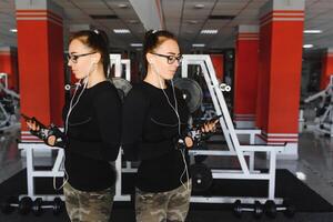 retrato do jovem desportista com Smartphone ouvindo para música dentro Academia foto