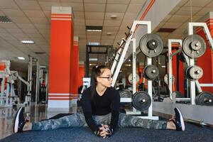 lindo fino morena fazendo alguns alongamento exercícios dentro uma academia. foto