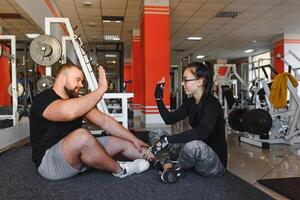 fitness, Esportes, exercícios e levantamento de peso. conceito - uma jovem mulher e uma jovem homem com halteres varrendo músculos dentro a Academia foto