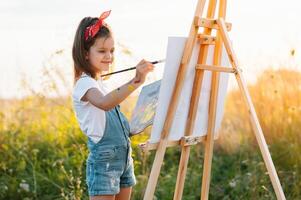 pequeno menina é pintura cenário ao ar livre. foto