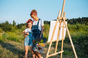 mãe ensina filha pintura dentro parque. ensolarado natureza, mãe e filha pintura uma cenário dentro uma parque , pintura uma pequeno criança, criança criatividade. mãe dia. foto