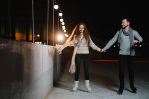 homem e mulher jovem família feliz sorrisos aguarde mãos patim em inverno rinque às noite, com bokeh luzes. foto