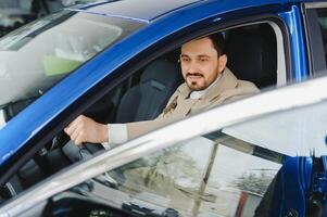 bonito barbudo homem de negocios é sentado dentro uma Novo carro dentro carro concessionária foto