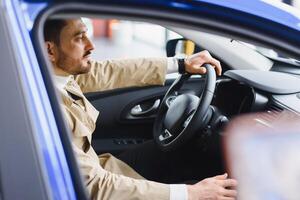 bonito barbudo homem de negocios é sentado dentro uma Novo carro dentro carro concessionária foto