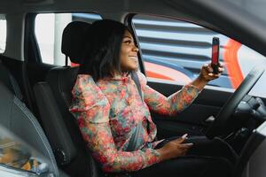 lindo Preto mulher fazendo selfie dentro a carro. lábios jovem mulher levando selfie cenário com inteligente telefone Câmera ao ar livre dentro carro foto
