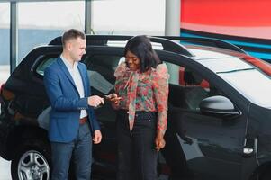 lindo jovem africano mulher comprando uma carro às concessionária foto