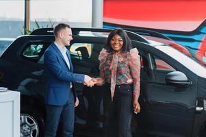 lindo jovem africano mulher comprando uma carro às concessionária foto