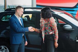 lindo jovem africano mulher comprando uma carro às concessionária foto