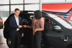 lindo jovem africano mulher comprando uma carro às concessionária foto