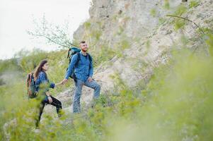 caminhante cara dá uma mão para a menina enquanto caminhando dentro a montanhas, Socorro e amizade conceito foto