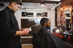 jovem afro-americano homem visitando barbearia foto
