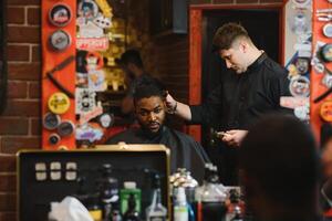 jovem afro-americano homem visitando barbearia foto