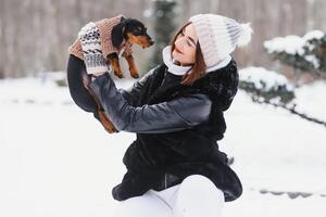 jovem à moda mulher com uma cachorro tendo Diversão dentro uma inverno floresta. foto