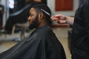 Preto homem dentro a barbearia. fofa Preto homem faz uma corte de cabelo dentro a africano salão. cabelo estilo. corte de cabelo para adultos. foto