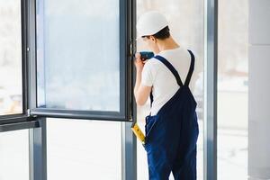 masculino industrial construtor trabalhador às janela instalação dentro construção construção local foto