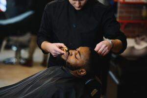 jovem afro-americano homem visitando barbearia foto