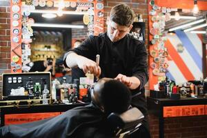 jovem afro-americano homem visitando barbearia foto