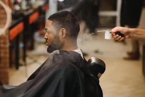 jovem afro-americano homem visitando barbearia foto