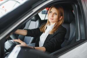 jovem lindo mulher mostrando dela amor para uma carro dentro uma carro showroom. foto