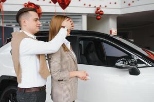 feliz jovem casal escolhe e comprando uma Novo carro para a família dentro a concessionária foto