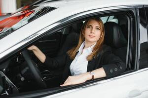 jovem lindo mulher mostrando dela amor para uma carro dentro uma carro showroom. foto