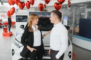 jovem casal usando uma carro dentro uma carro showroom. foto