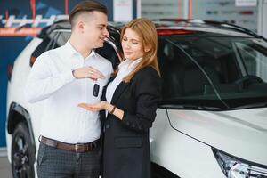 jovem casal usando uma carro dentro uma carro showroom. foto