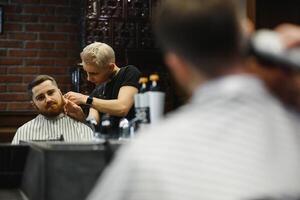 fazer corte de cabelo Veja perfeito. jovem barbudo homem obtendo corte de cabelo de cabeleireiro enquanto sentado dentro cadeira às barbearia. foto