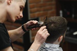 fazer corte de cabelo Veja perfeito. jovem barbudo homem obtendo corte de cabelo de cabeleireiro enquanto sentado dentro cadeira às barbearia. foto