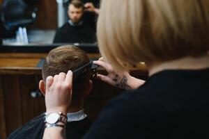 barbeiro mulher corte homem cabelo às a barbearia. mulher trabalhando Como uma cabeleireiro. pequeno o negócio conceito foto