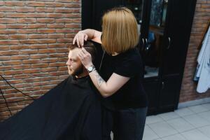 mulher barbeiro corte cabelo para uma barbudo homem foto