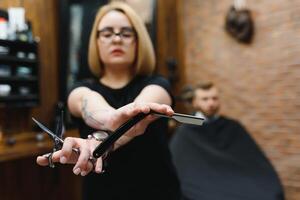 retrato do moda mulher barbeiro estilista de cabelo com tesouras dentro mão dentro a barbearia foto