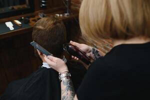 barbeiro mulher corte homem cabelo às a barbearia. mulher trabalhando Como uma cabeleireiro. pequeno o negócio conceito foto