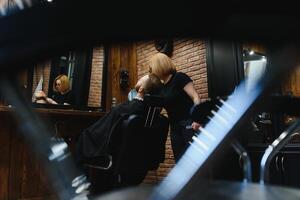 barbearia ou cabeleireiro conceito. mulher cabeleireiro cortes barba com tesoura. homem com grandes barba, bigode e à moda cabelo. cara com moderno Penteado visitando cabeleireiro foto