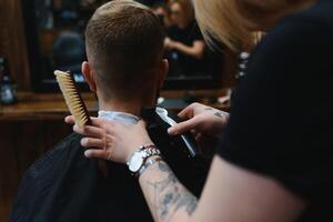 à moda homem sentado barbeiro fazer compras estilista de cabelo cabeleireiro mulher corte dele cabelo retrato bonito feliz jovem barbudo caucasiano cara obtendo na moda corte de cabelo atraente barbeiro menina trabalhando servindo cliente foto