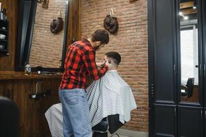 bonito barbudo homem é sorridente enquanto tendo dele cabelo cortar de cabeleireiro às a barbearia foto