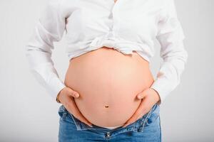 grávida mulheres tocante dela barriga com mão foto