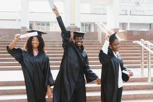 Educação, graduação e pessoas conceito - grupo do feliz internacional alunos dentro argamassa Pranchas e solteiro vestidos com diplomas foto