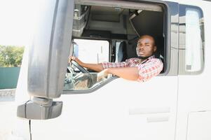 caminhão motorista homem africano americano muscular sorridente, dentro muito tempo o negócio transporte e Entrega foto