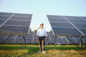 retrato jovem indiano técnico ou Gerente vestindo formal panos em pé com solar painel. renovável energia, homem em pé cruzado braço, cópia de espaço foto