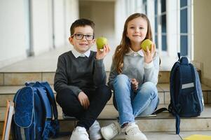 grupo do colegas de classe tendo almoço durante pausa com foco em sorridente menina com maçã. foto